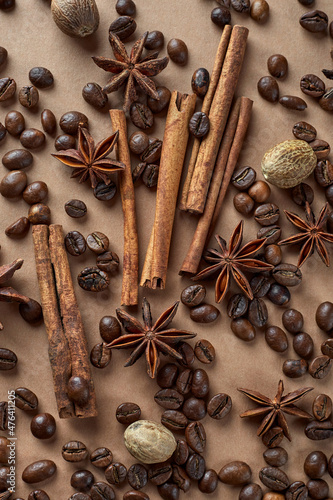 Roasted coffee beans, cinnamon sticks, star anise and nutmeg on a brown background. The grains and spices are in no particular order