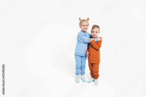 A little girl and a boy hug. Children's love. On a monochromatic background, children in sportswear. Blue tracksuit