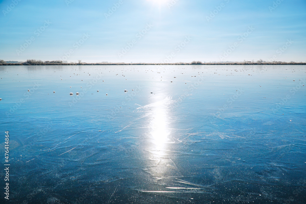 Sun in the blue sky over a frozen winter lake.. Fabulous Winter landscape