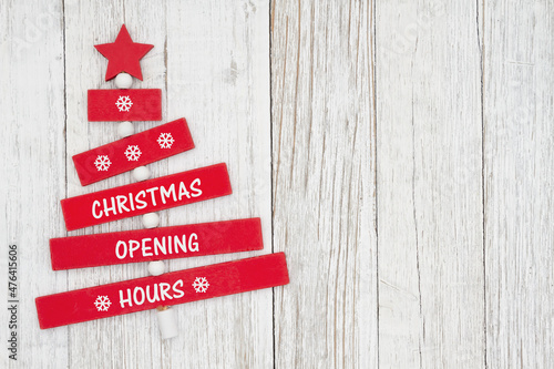 Christmas Opening Hours sign on red wood Christmas tree with weathered wood