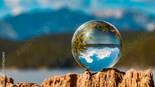 Crystal ball alpine summer landscape shot on a tree stump at the famous Eibsee lake near Garmisch-Partenkirchen, Bavaria, Germany