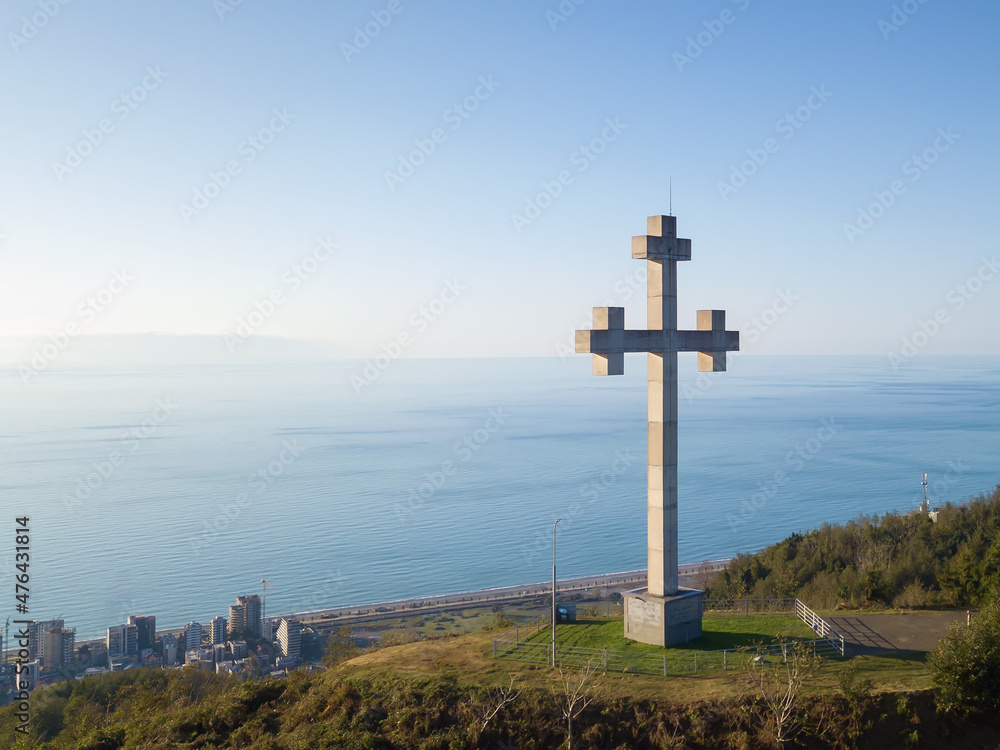 Drone view of the Orthodox cross on the mountain against the background of the sea on a sunny evening, Georgia. Concept of freedom, Christianity, Orthodoxy