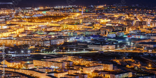Panorama of the night city. A beautiful night top view of the illuminated streets and buildings. Aerial view of residential areas. Many panel buildings. Magadan, Magadan Region, Far East of Russia.