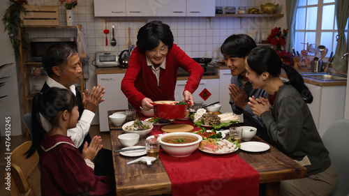 Foto happy grandmother serving delicious food on dining table as her family members clapping hands for her