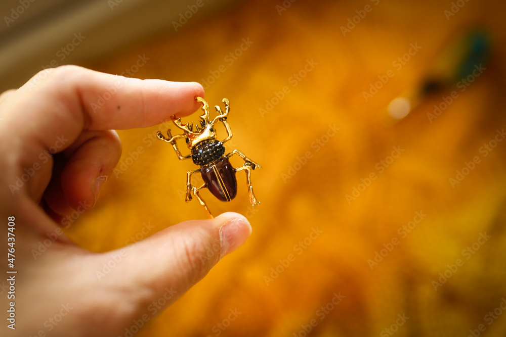 Obraz premium brooch jewelry Insect breaks on a yellow knitted sweater, an inexpensive jewelry jewelry in the entomological style