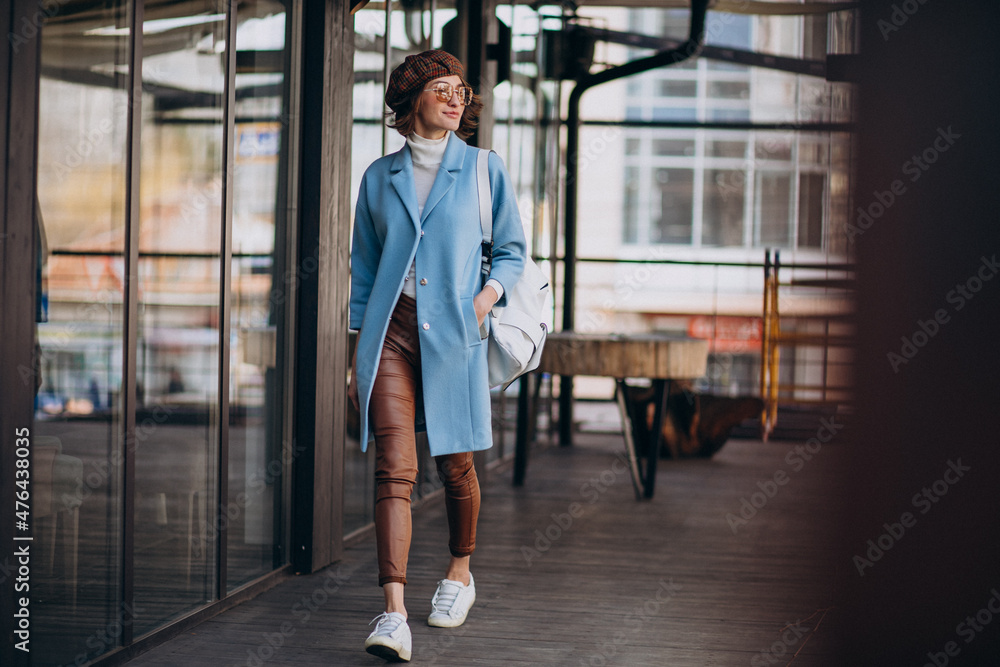 Fototapeta premium Young woman model in blue coat by the cafe