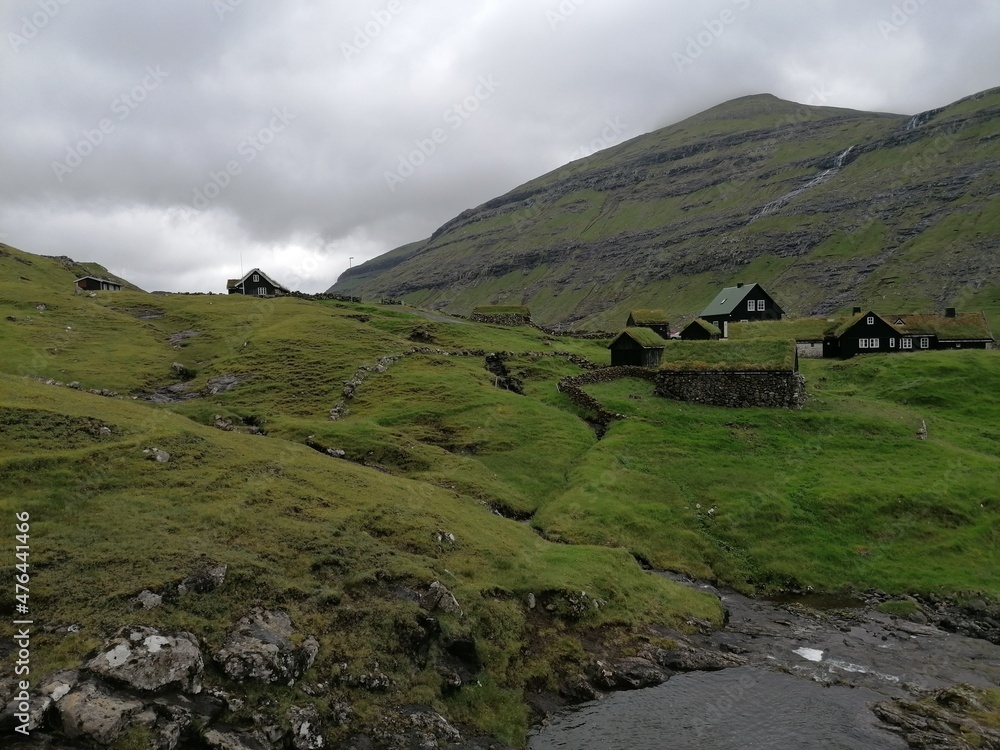 Traditional old cute stone houses with grass roofs on the Faroe Islands with a mountain view