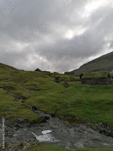 Traditional old cute stone houses with grass roofs on the Faroe Islands with a mountain view