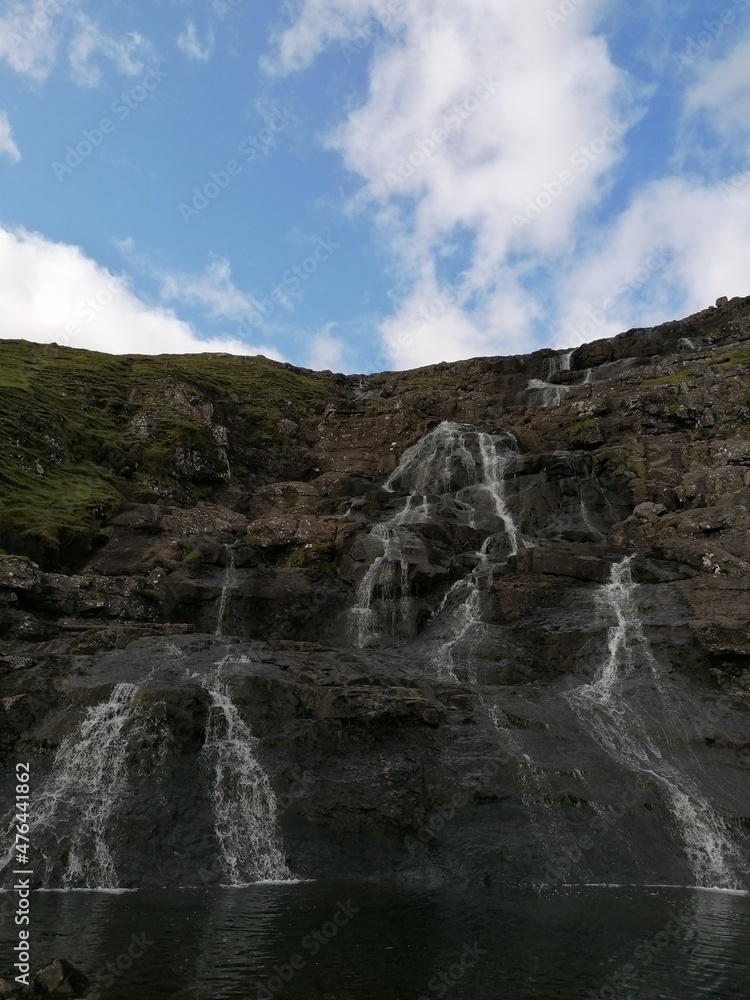 Fototapeta premium Stunning waterfalls with white streams coming down over black lava rocks on the Faroe Islands 