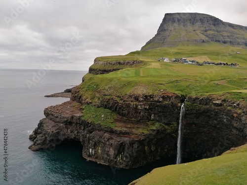 Stunning waterfalls with white streams coming down over black lava rocks on the Faroe Islands 