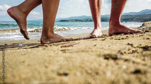 Two pairs of feet standing at the golden sand of Lara Beach, Cyprus. Hidden gem, not spoiled by tourists. Solitude and calm feelings, waves gently spreading on the beach. turquoise color of the water. photo