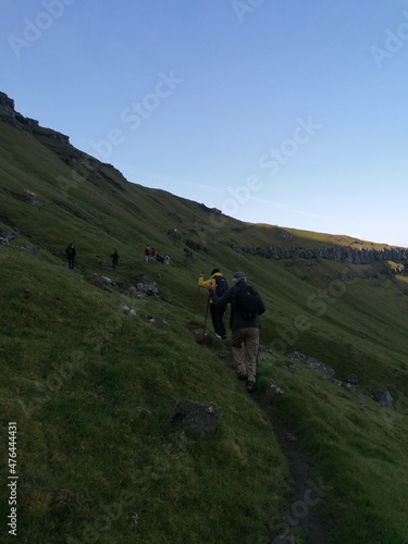 A group of hikers on a green mountain ridge walk in the Faroe Islands
