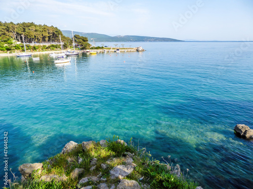 A beautiful view on the coastal line from a little cliff. The water has very deep color. On the sides of the cliff there are coniferous trees. There is a small city on the other side of the shore. © Chris