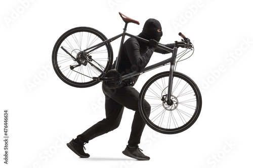 Fotografie Full length profile shot of a burglar in black clothes with a balaclava stealing