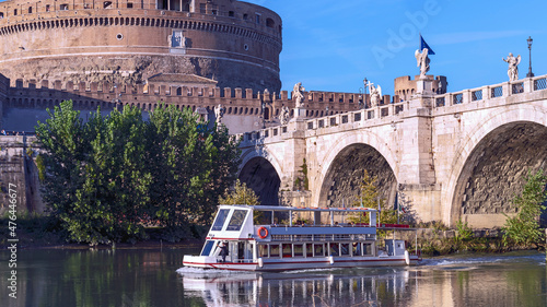 the cruise ship floats on the river against the background of the bridge with sculptures of angels and the Castel Sant'Angelo