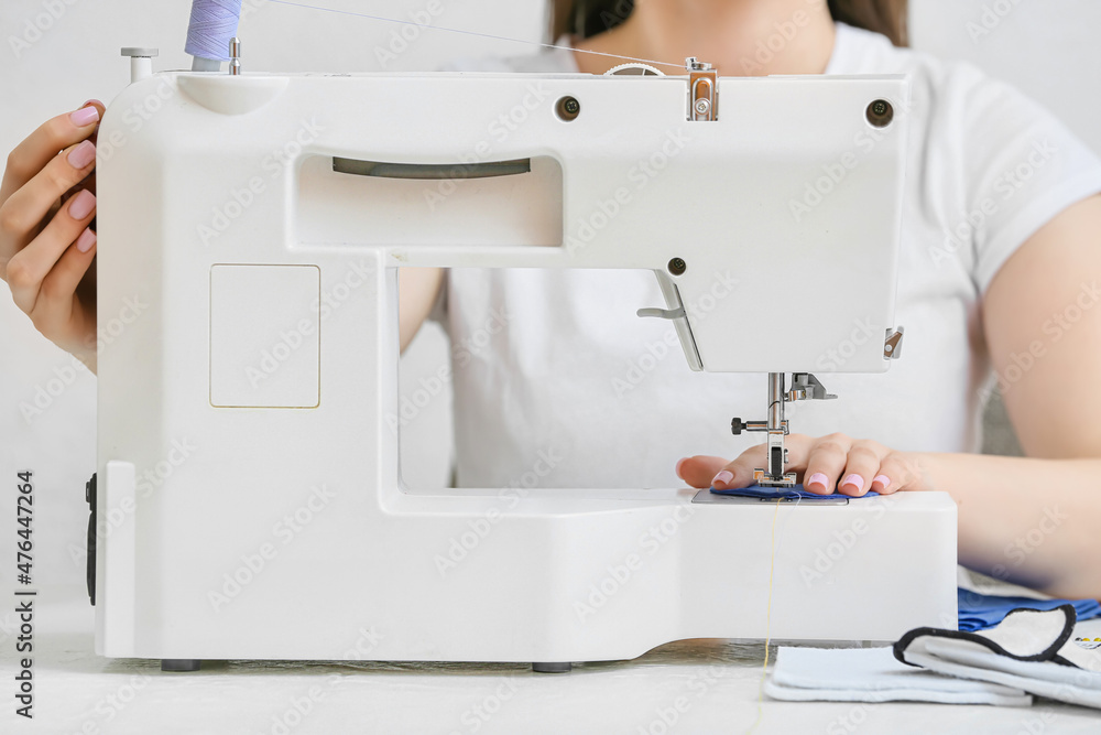 Woman with sewing machine making reusable cotton pad at table, closeup