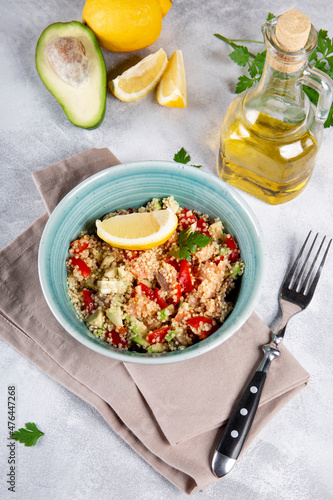  Salmon salad with tomatoes, avocado and quinoa in a blue bowl on a light gray table vertical photo, a dish of balanced diet