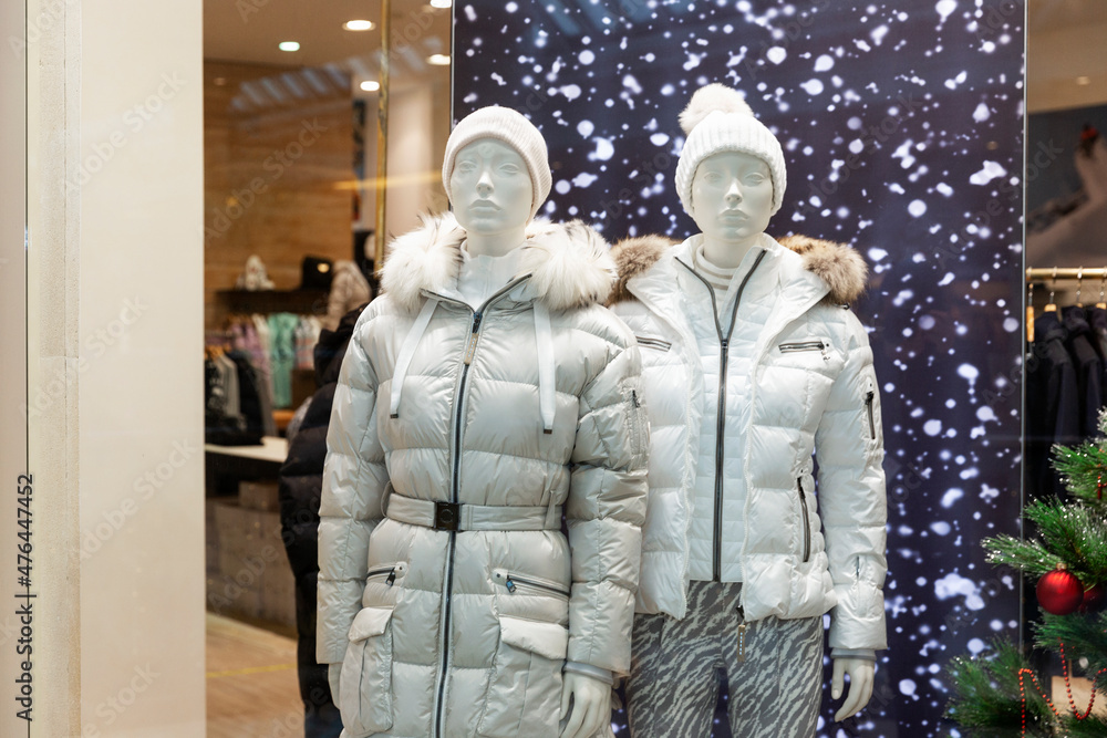 Fototapeta premium Male and female mannequins in stylish winter white clothes in a New Year's shop window.