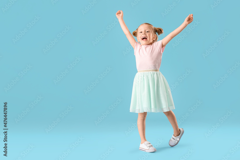 Cute little girl in skirt dancing on blue background Cute little girl in skirt dancing on blue background