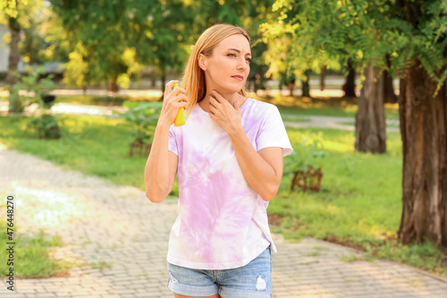 Foto Mature woman with mosquito repellent in park