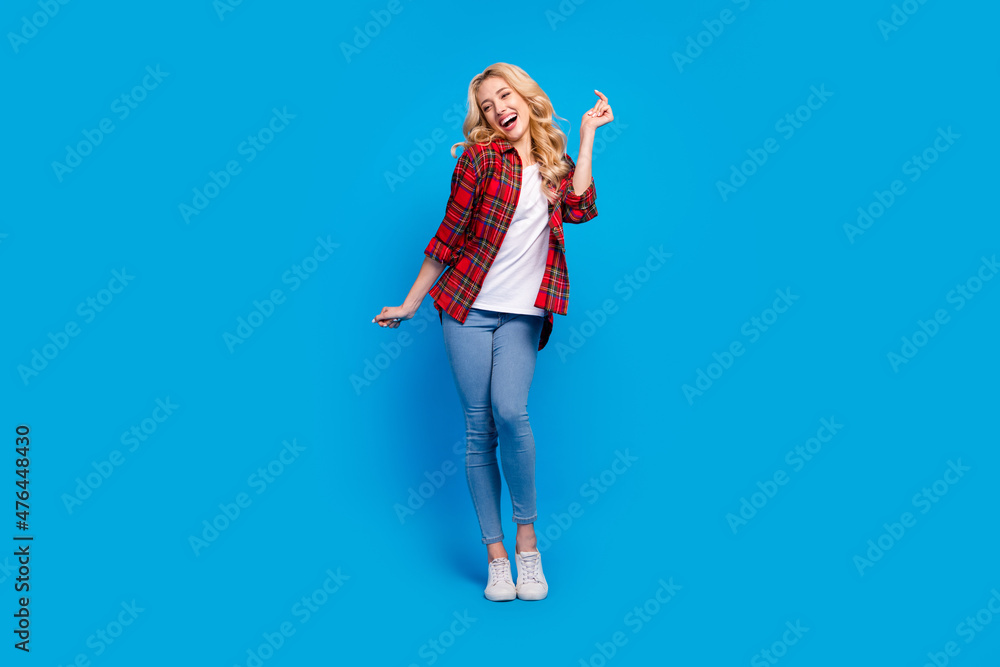 Photo of charming funky young woman dressed checkered shirt dancing smiling isolated blue color background Photo of charming funky young woman dressed checkered shirt dancing smiling isolated blue color background