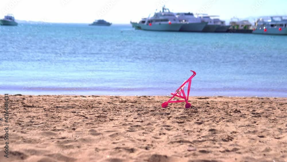 toy baby carriage standing on the sand near the sea, safety in the water concept toy baby carriage standing on the sand near the sea, safety in the water concept