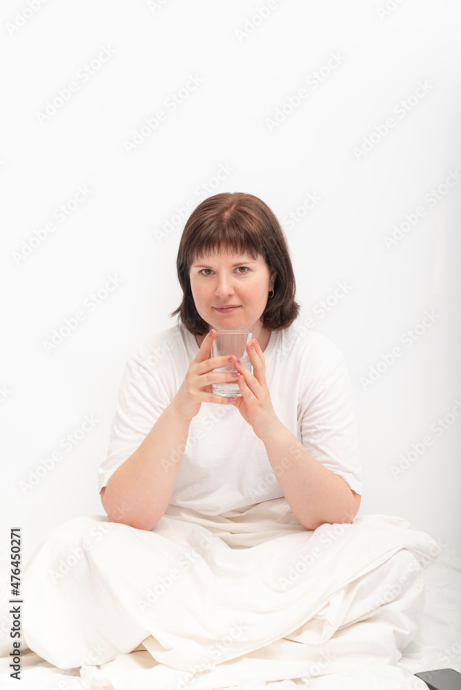 Portrait of young caucasian woman in bed with glass of water. Habit of drinking water in the morning. Portrait of young caucasian woman in bed with glass of water. Habit of drinking water in the morning.