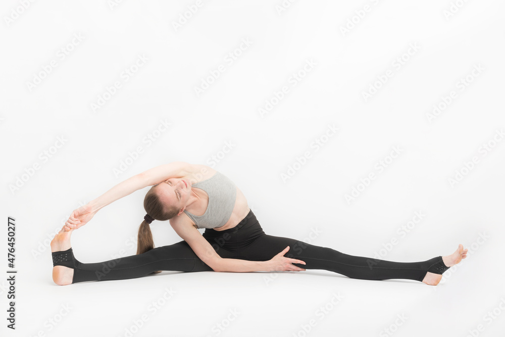Teenage girl is engaged in gymnastics. Dancer in training on white background. Exercise to develop flexibility. Teenage girl is engaged in gymnastics. Dancer in training on white background. Exercise to develop flexibility.
