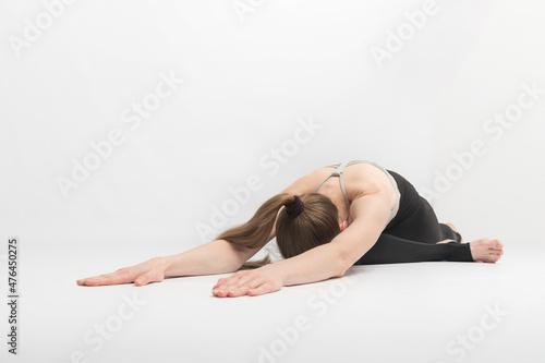 Adho Mukha Kapotasana. Downward Facing Pigeon. Girl practices yoga asanas on white background. Young woman is engaged in gymnastics.