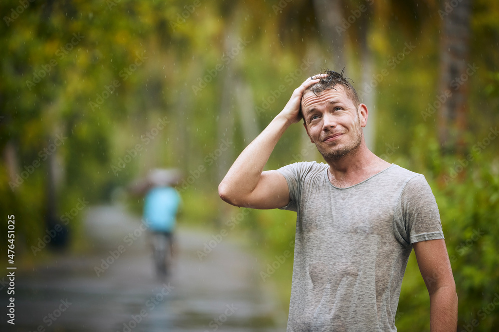 Obraz premium Portrait of drenched young man enjoying heavy rain in nature..