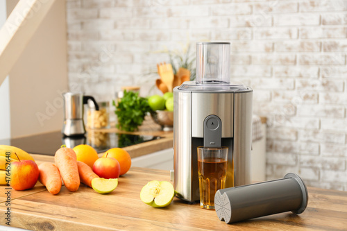 Modern juicer with fresh fruits on table in kitchen photo