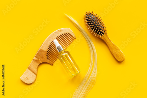 Hair essential oil with wooden brush and blond curl of hair