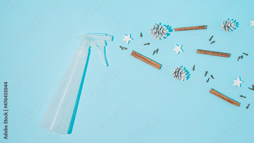 Creative arrangement made of a bottle sprayer and Christmas things, cinnamon, cloves, pine cones and stars on a blue background. Minimal New Year concept. Christmas scents and cleaning inspiration. Creative arrangement made of a bottle sprayer and Christmas things, cinnamon, cloves, pine cones and stars on a blue background. Minimal New Year concept. Christmas scents and cleaning inspiration.