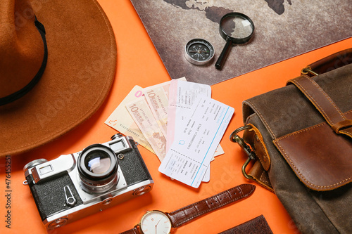 Travelling belongings with money, tickets and world map on color background