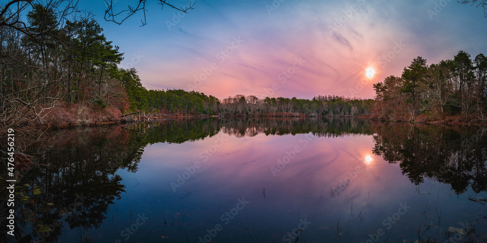 Sunrise over the pine tree forest and glacial kettle pond on Cape Cod