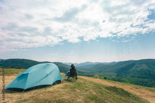 Young people camping tent with sitting on chairs with picnic table on the mountain. Camping on the mountain.