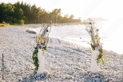 Wedding semi-arch with floral decor on a pebble beach