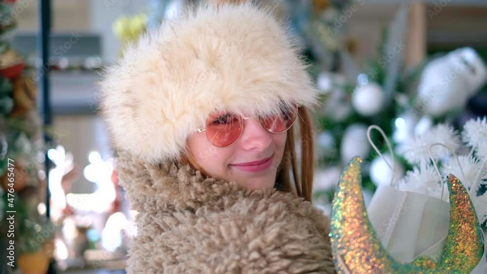 Winter sale or Christmas shopping concept. Attractive girl in warm clothing and sunglasses happy portrait in store or supermarket. New Year shopping or consumerism theme. High quality 4k video footage Winter sale or Christmas shopping concept. Attractive girl in warm clothing and sunglasses happy portrait in store or supermarket. New Year shopping or consumerism theme. High quality 4k video footage