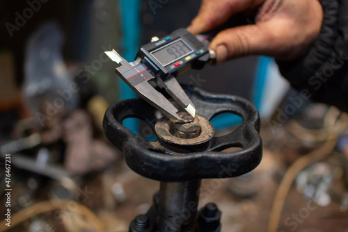 A locksmith using a vernier caliper makes measurements of the valve.