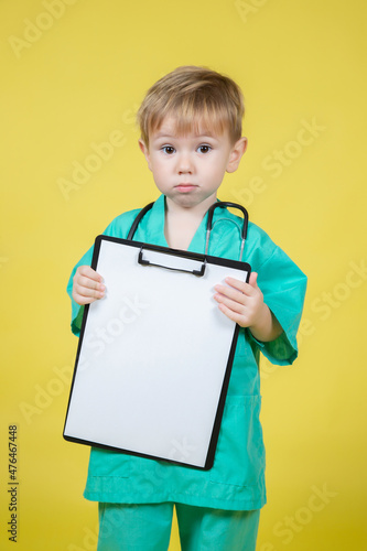 Portrait of little kid dressed in doctors green coat holds tablet in hand