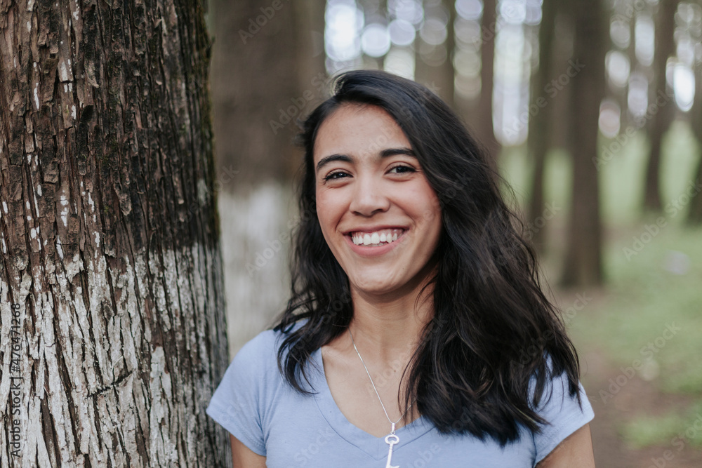 Mujer joven con pelo largo sonriendo en bosque Mujer joven con pelo largo sonriendo en bosque