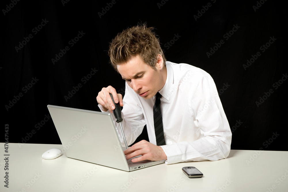 Geschäftsmann repariert Laptop mit Schraubenzieher  