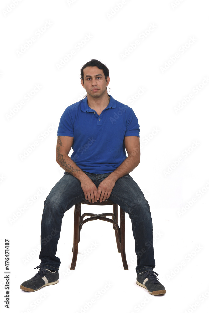 front view of man with ponytail and casual clothing  and tattoos sitting a chair on white background