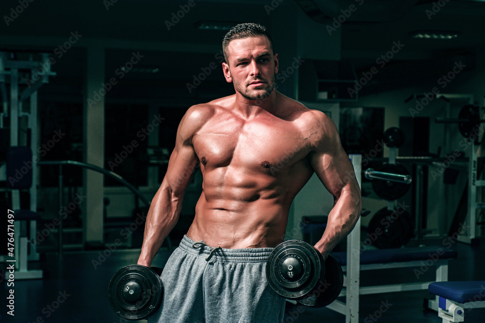 Man in gym. Muscular and strong guy exercising. Sportsman doing exercises with weights. Fitness and crossfit.