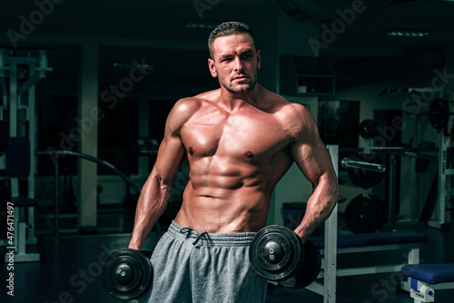 Man in gym. Muscular and strong guy exercising. Sportsman doing exercises with weights. Fitness and crossfit.