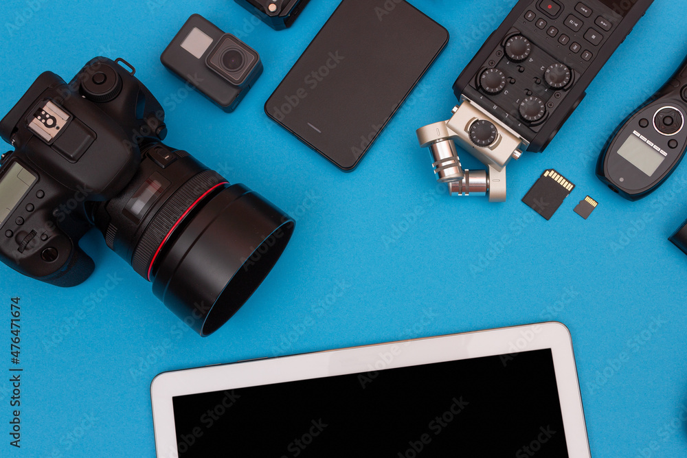 Top View of Photographer's, Videographer's or Video Blogger's Workplace. Digital Gadgets Lying on Blue Table - Flat Lay Top View of Photographer's, Videographer's or Video Blogger's Workplace. Digital Gadgets Lying on Blue Table - Flat Lay