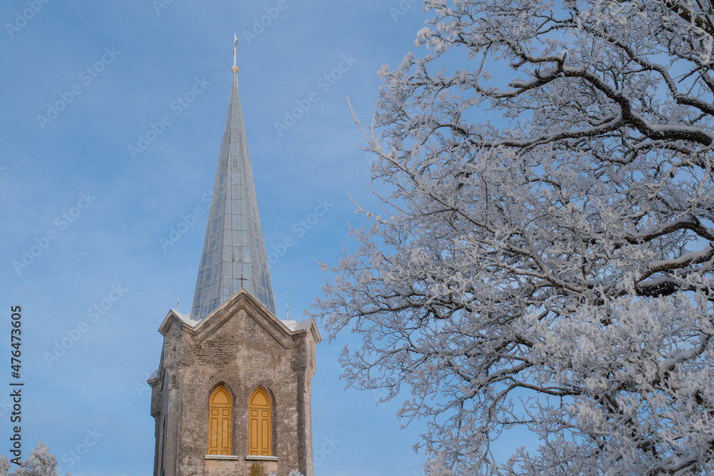 The steeple of the Church of the Blessed Virgin Mary in Joelahtme (Estonian - Püha Neitsi Maarja kirik, Jõelähtme) on a sunny winter morning. One of the oldest churches in Estonia.
