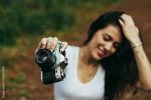 woman holding old camera in the middle of the forest photo