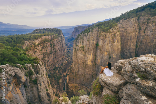 Valokuva Tourist woman in white dress sitting on the edge of a cliff against the backdrop of a gorge
