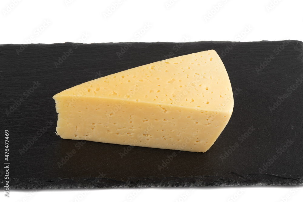 A piece of hard cheese on a stone cutting board. A piece of hard cheese on a stone cutting board.
